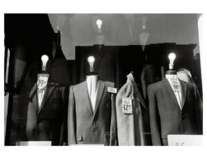 Headless suit mannequins with light bulbs for heads in a NYC store window, 1959.